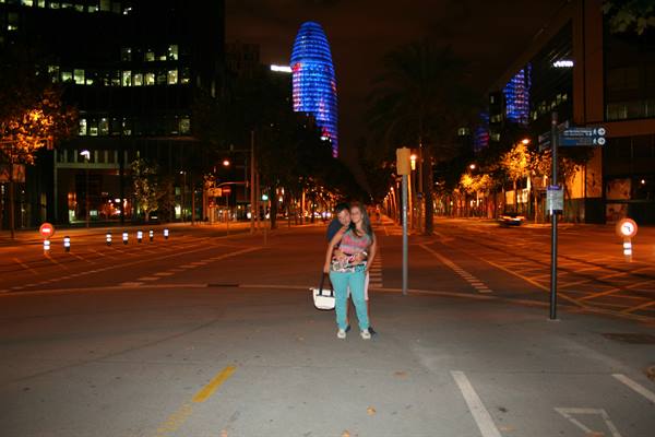Two girls on a Barcelona street at night with the lit Torre Agbar