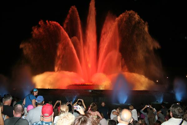 Magic Fountain of Montjuïc in Barcelona, red illuminated water jets at night among crowds