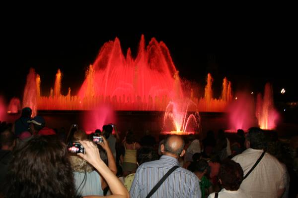 Montjuïc magic fountain glowing red at night, tourists taking photos