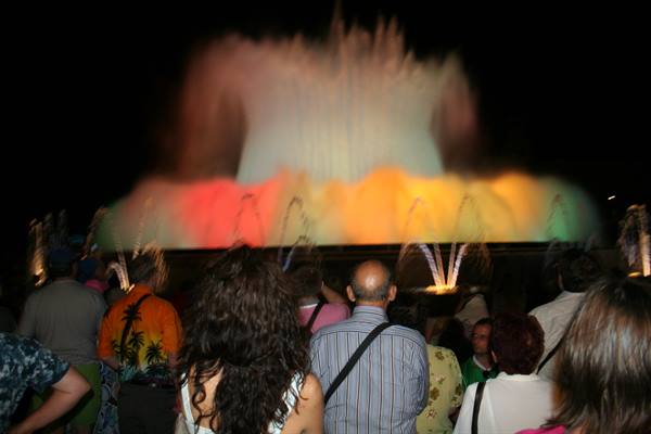 Crowd watching the illuminated Montjuïc fountain with colorful water jets at night