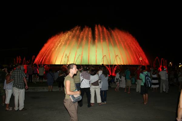 Tourists watch the Magic Fountain of Montjuïc lit in red and green