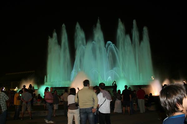 Tourists watch the illuminated Montjuïc fountain glowing green at night