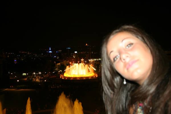 Smiling girl at night in front of the illuminated Magic Fountain of Montjuïc