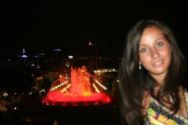Smiling girl in front of the Magic Fountain of Montjuïc glowing red, Barcelona