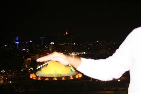 outstretched hand in front of an illuminated fountain at night