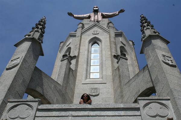 Tourist beneath the Christ statue on the Temple del Sagrat Cor, Tibidabo, Barcelona