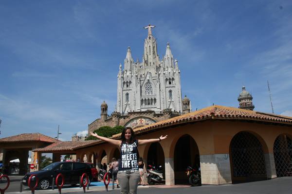 Girl with open arms in front of the Sagrat Cor temple on Tibidabo