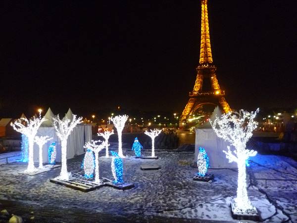 Illuminated Christmas trees and penguin displays in front of the Eiffel Tower