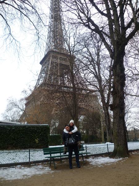 Couple hugging in front of the Eiffel Tower, snow on ground, bare trees