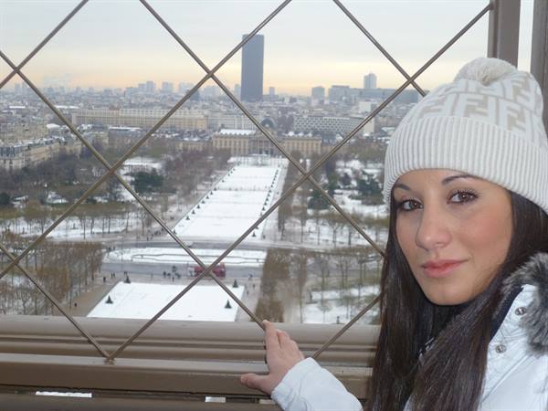 Woman in white beanie atop the Eiffel Tower, snowy Champ de Mars below
