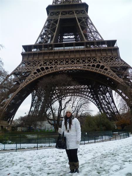 Woman in white down jacket on snow beneath the Eiffel Tower