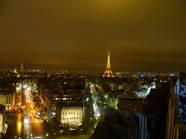 The illuminated Eiffel Tower at night above Paris rooftops