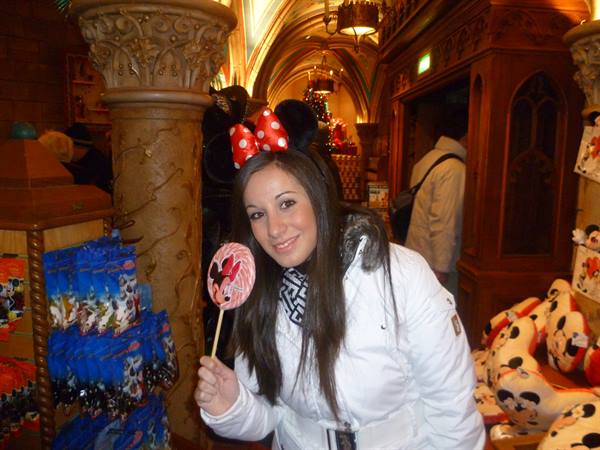 Girl wearing Minnie ears holding a pink lollipop in a Disneyland shop