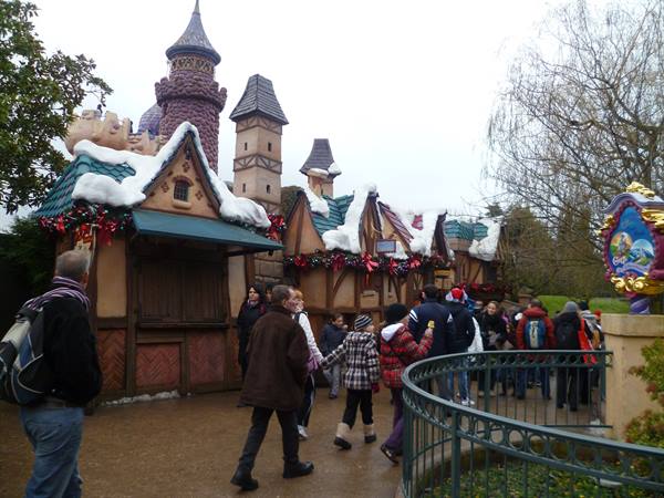 Visitors queueing by snow-covered fairytale cottages at Disneyland