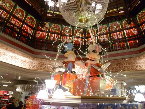 Winter Mickey and Minnie among glowing gifts under a crystal chandelier