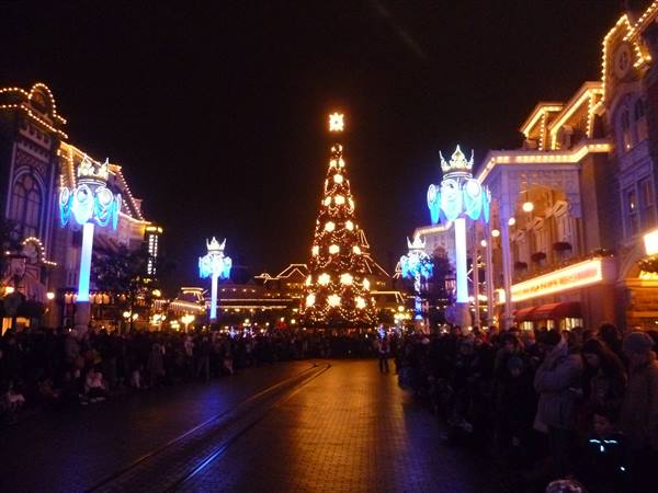 Illuminated Christmas tree on Disneyland's Main Street, crowd of visitors