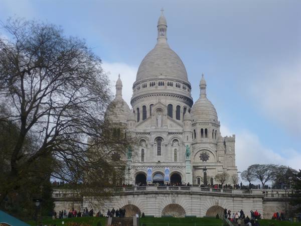 The Sacré-Cœur basilica in Paris, white among bare trees and visitors