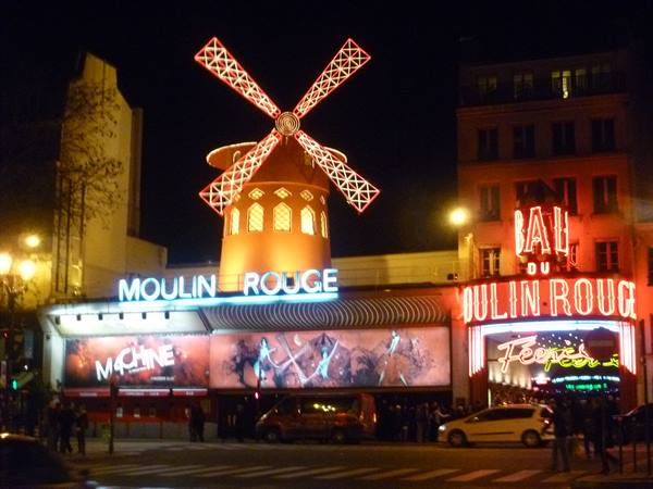 The Moulin Rouge lit by red neon signs at night in Paris
