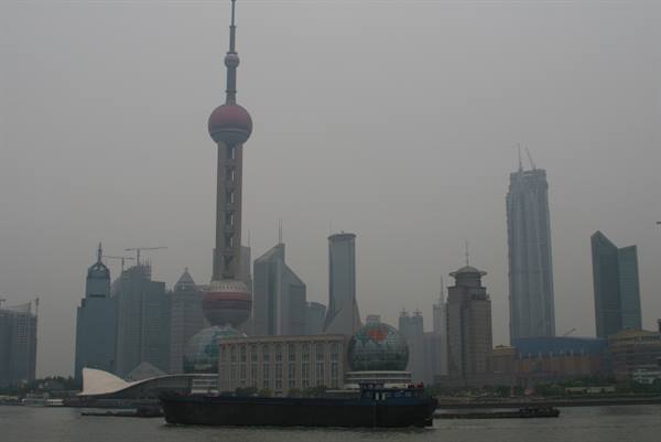 Oriental Pearl Tower and Pudong skyscrapers in haze, a barge on the Huangpu river