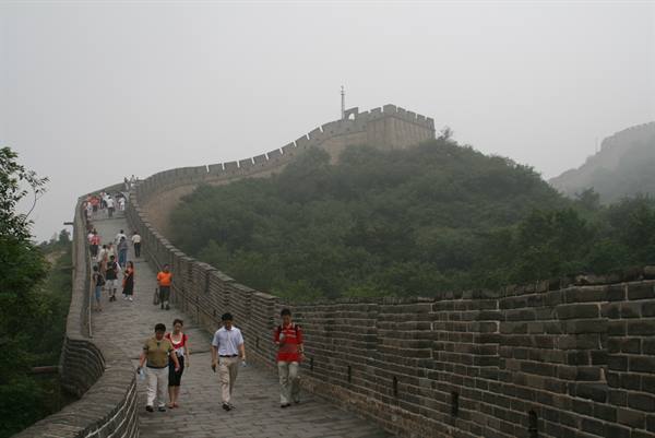 Tourists walk on the stone Great Wall under foggy skies