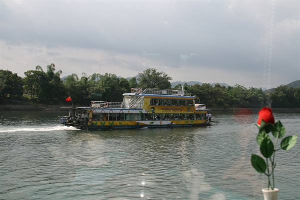 Yellow ferry crossing the river, artificial rose on the table