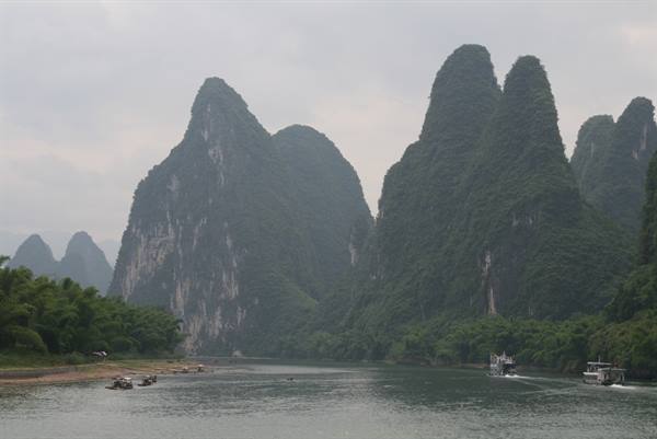 Boats on the river among karst peaks of Guilin under grey sky