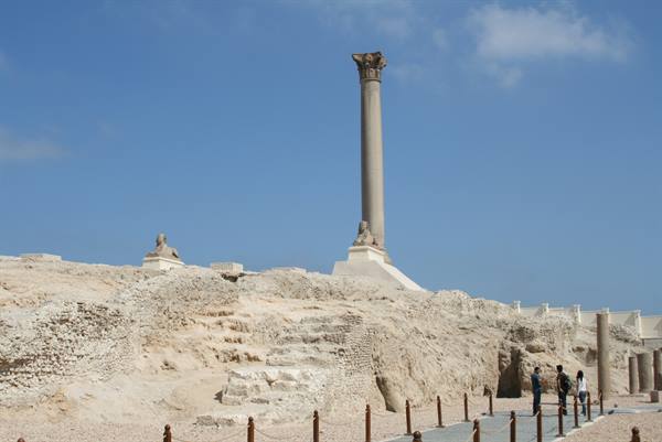 Pompey's Pillar in Alexandria, standing among ruins and stone sphinxes