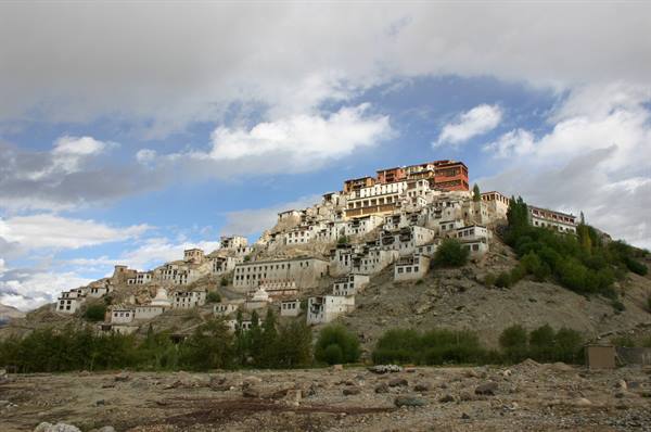 Thiksey Monastery, whitewashed and ochre buildings crowding the hillside under clouds