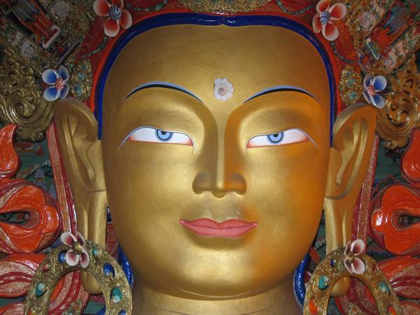 Golden face of Maitreya Buddha with blue eyes, colorful floral ornaments
