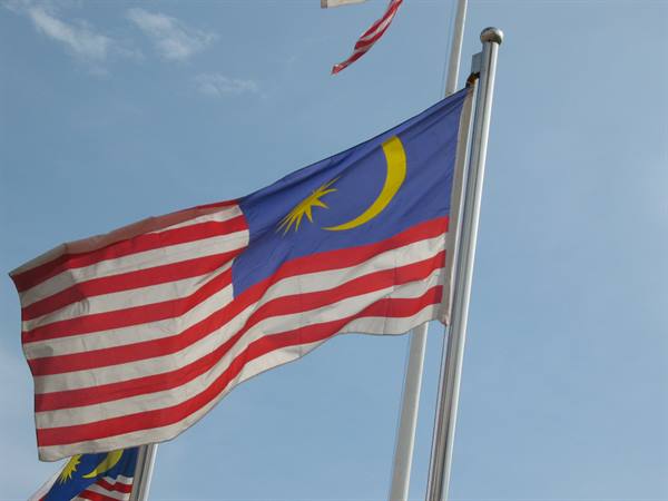 Malaysian flag with yellow crescent and star waving on a pole