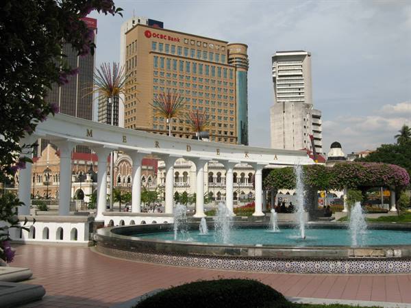 Fountain and colonnade inscribed Merdeka in Kuala Lumpur, skyscrapers behind