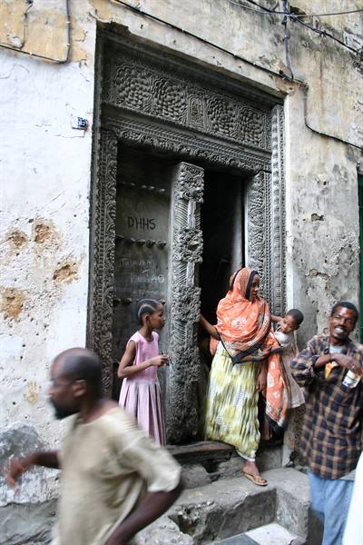 Family by a carved wooden door in Stone Town