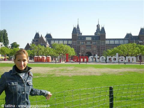 Tourist next to the I amsterdam sign in front of the Rijksmuseum, green lawn