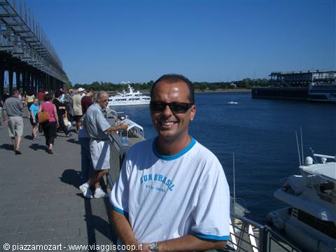 Man in sunglasses on busy pier, yachts and river under summer sun