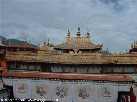Golden roof of Jokhang Temple in Lhasa, stupas and mountains behind