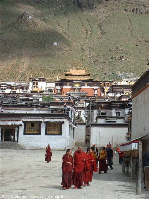 Monks in crimson robes walk through Tashilhunpo monastery courtyard