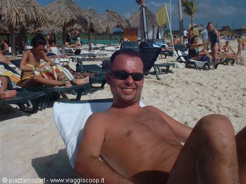 Tourist in sunglasses relaxing on a lounge chair under beach palapas