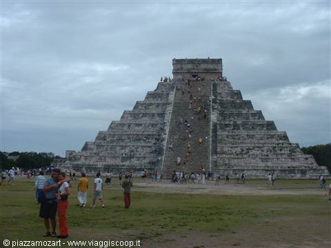 Tourists climbing the staircase of El Castillo pyramid at Chichén Itzá under cloudy sky