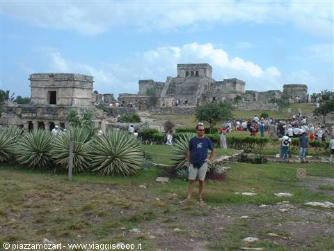 Tourist standing among agaves in front of the Mayan ruins of Tulum