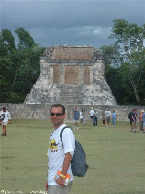 Tourist with backpack in front of the stone pyramid at Chichén Itzá under cloudy sky