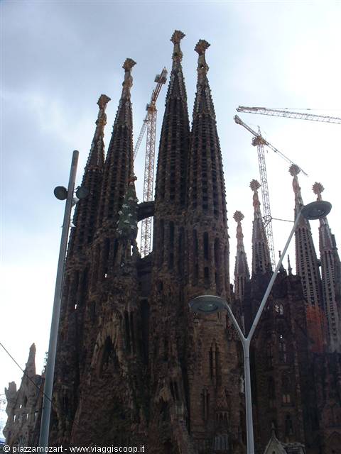 Sagrada Família towers surrounded by cranes against a grey sky