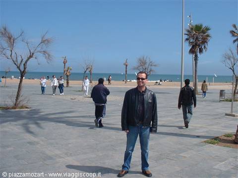 Man in leather jacket on seaside promenade with palms and beach, Valencia