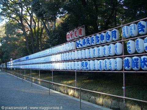 Rows of white paper lanterns with blue calligraphy on metal racks