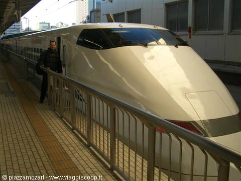 Traveler beside the white nose of a Shinkansen stopped at the station