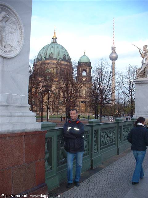 Man leaning on green railing with Berlin Cathedral and TV Tower behind