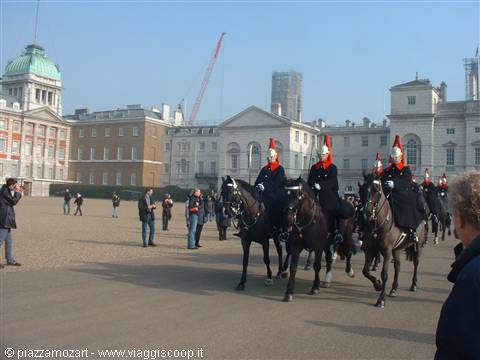 Mounted guards in red helmets parade on black horses at Horse Guards, London