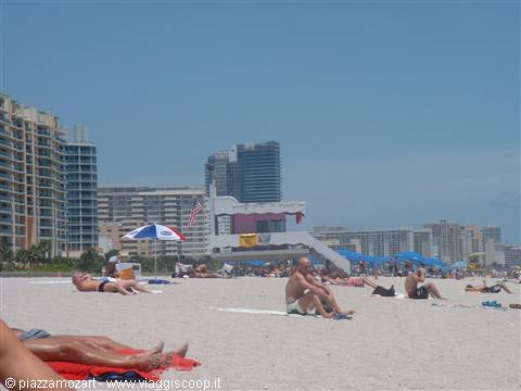Lifeguard tower and sunbathers under umbrellas on the sand, Miami Beach