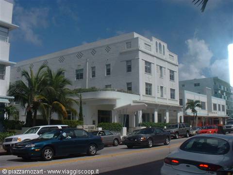 White Art Deco building along Ocean Drive, palm trees and cars in traffic