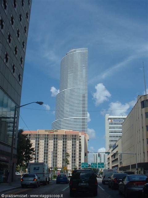 Curved glass skyscraper rising above traffic on Biscayne Boulevard, Miami