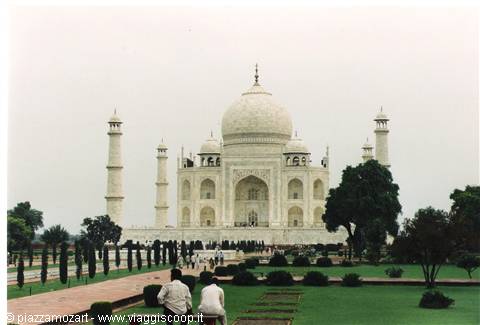 Tourists sitting on garden path in front of white marble Taj Mahal
